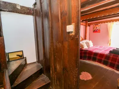 a bedroom with a bed with a red blanket at The Little Laura Ashley House in Machynlleth