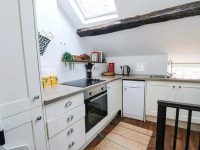 a kitchen with white cabinets and a skylight at The Little Laura Ashley House in Machynlleth