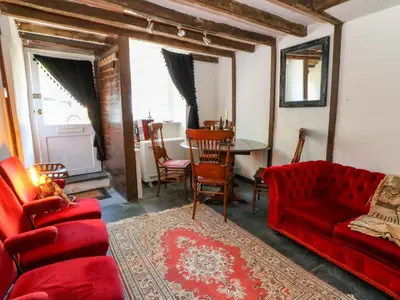 a living room with a red couch and a table at The Little Laura Ashley House in Machynlleth