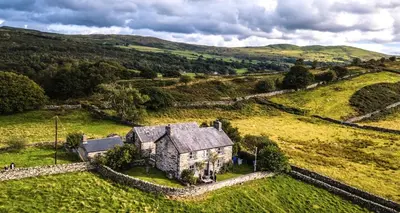 an old house in the middle of a field at Large farmhouse in Snowdonia, North Wales in Talsarnau
