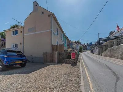 a blue car parked next to a building on a street at Spring Gardens in New Quay