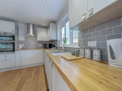 a kitchen with white cabinets and a wooden counter top at Spring Gardens in New Quay