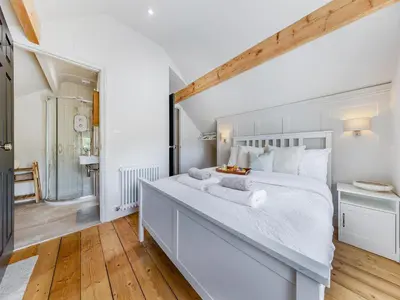 a white bedroom with a large bed and a bathroom at Lansdowne House in Brecon