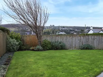 a backyard with a fence and a green yard at Hafod Y Morfa - Uk48829 in Harlech