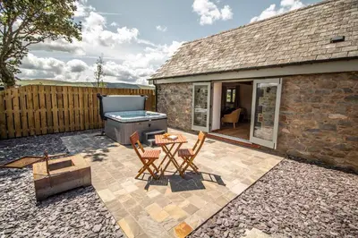 a patio with a table and chairs and a barbecue at Wyns Barn in Rhayader
