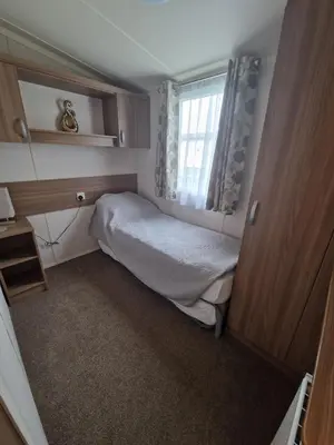 a small bedroom with a bed and a window at Green Heaven at Clarach Bay Spacious 3 BedPet Friendly Luxury Steps from the Sea in Aberystwyth
