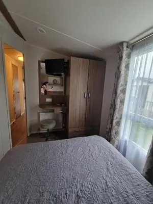 a bedroom with a bed and a desk and a television at Green Heaven at Clarach Bay Spacious 3 BedPet Friendly Luxury Steps from the Sea in Aberystwyth