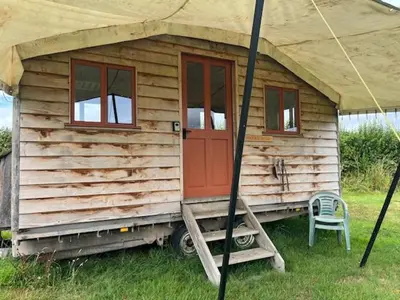 a small wooden cabin with a chair in the grass at Tinkers Horn Cabin in Kington