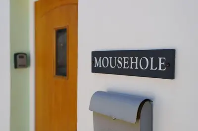 a sign on a wall next to a door at Mousehole in Aberdyfi Charming Seaside Fisherman's Cottage in Aberdyfi