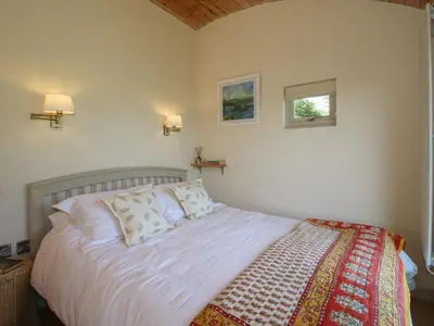 a bedroom with a bed with white sheets and a window at Squirrel's Drey in Bucknell