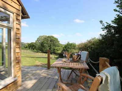 a wooden deck with a table and chairs on it at Squirrel's Drey in Bucknell