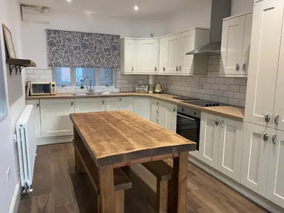 a kitchen with white cabinets and a wooden table at Town centre Victorian period 3 bedroom home in Bishops Castle