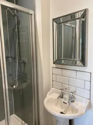 a bathroom with a sink and a shower and a mirror at Town centre Victorian period 3 bedroom home in Bishops Castle