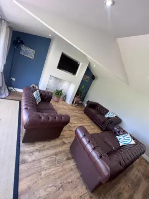 a living room with two leather couches and a television at Awel Y Trydan Cottage in Pennant