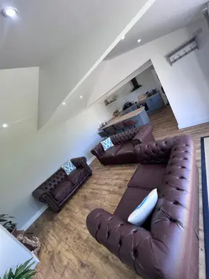 a living room with a leather couch and two couches at Awel Y Trydan Cottage in Pennant