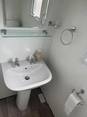 a white bathroom with a sink and a mirror at Static Caravan in Aberystwyth