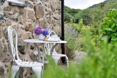 a table with two chairs and flowers on it at Finest Retreats - Penclogwynau in Dolgellau