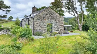 an old stone house in a field with a garden at Finest Retreats - Penclogwynau in Dolgellau