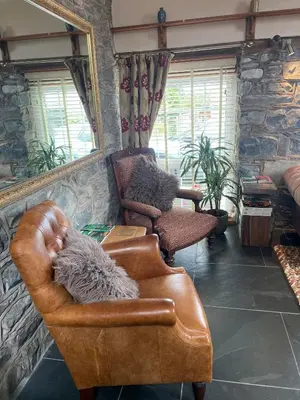 a living room with a leather chair and a mirror at Y Bwthyn in Llanfihangel-geneuʼr-glyn