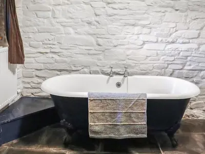 a black and white bath tub in a bathroom at Thatched Cottage - Uk50261 in Llandeilo