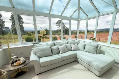 a white couch in a room with windows at Wellingtonia Cottage in Chirbury