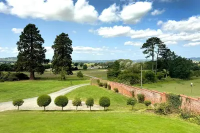 a view of a field with trees and a road at Wellingtonia Cottage in Chirbury