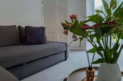 a living room with a couch and a vase with flowers at Charming Eco Hideaway on the Dee River with Private Relaxing Hot Tub in Llangollen