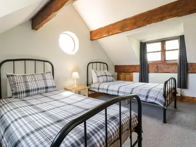 two beds in a room with a window at Cyffdy Cottage - Aran in Bala