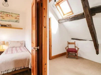 a bedroom with a bed and a window and a chair at Cyffdy Cottage - Tegid in Bala