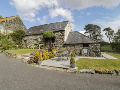 a stone house with a table and chairs in front of it at Cyffdy Cottage - Tegid in Bala
