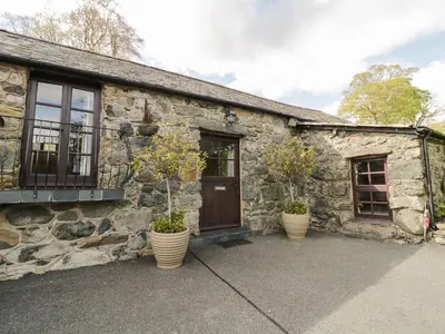 a stone house with two potted plants in front of it at Cyffdy Cottage - Arenig in Bala