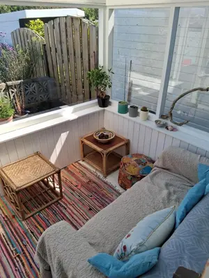 a porch with a couch and a table and a window at King bed, opposite the beach in Borth