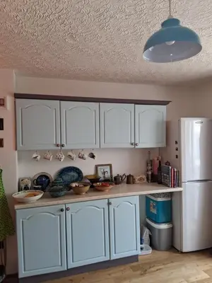 a kitchen with white cabinets and a white refrigerator at King bed, opposite the beach in Borth