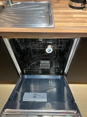an open dishwasher with a box in it under a counter at two bed Seafront apartment - sea views in Aberystwyth