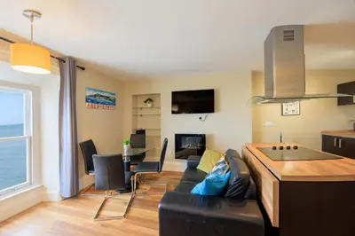 a living room with a black couch and a table at two bed Seafront apartment - sea views in Aberystwyth