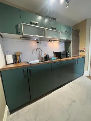 a kitchen with green cabinets and a sink at two bed Seafront apartment - sea views in Aberystwyth