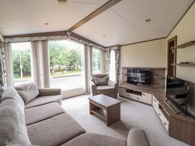 a living room with a couch and a tv at Beach Retreat E19 Dyffryn Seaside Estate in Dyffryn