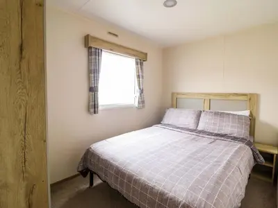 a bedroom with a bed and a window at Beachcombers Barmouth Bay Holiday Park in Talybont