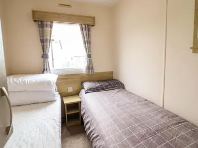 two beds in a small room with a window at Beachcombers Barmouth Bay Holiday Park in Talybont