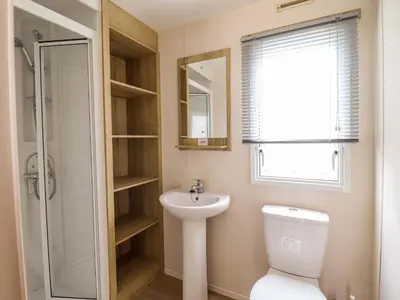 a bathroom with a toilet and a sink and a mirror at Beachcombers Barmouth Bay Holiday Park in Talybont