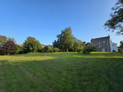 a large grass field with a building in the background at Modern Retreat near Aberaeron - Luxe 1 bed Escape in Ciliau-Aeron