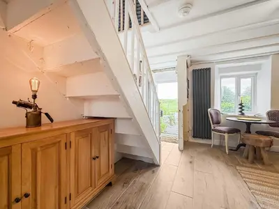 a room with a staircase and a table and chairs at Tegfryn Cottage in Tanygrisiau
