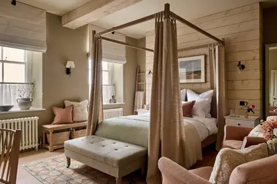 a bedroom with a canopy bed and a chair at Castle Corner, The Georgian House in Ludlow
