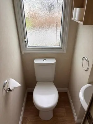a bathroom with a toilet and a window at Clarach Bay Escape 3 Bedroom PetFriendly Caravan with Decking Sleeps 6 in Aberystwyth
