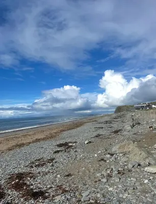 a beach with rocks and the ocean on a cloudy day at Clarach Bay Escape 3 Bedroom PetFriendly Caravan with Decking Sleeps 6 in Aberystwyth