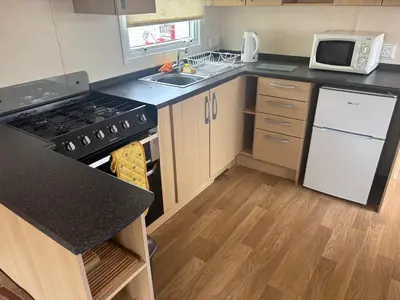 a kitchen with a stove and a sink and a refrigerator at Clarach Bay Escape 3 Bedroom PetFriendly Caravan with Decking Sleeps 6 in Aberystwyth