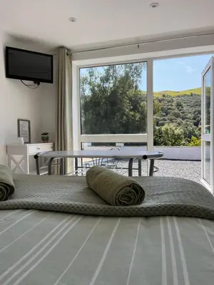 a bedroom with a large window and a table at Forest View Annexe in Ponterwyd