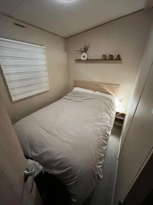 a small bedroom with a white bed and a window at Gold Plus 3 Bed ABI Summer Breeze Modern Caravan with Sea View Pet Friendly in Aberystwyth
