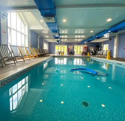 a large swimming pool with chairs in a building at Gold Plus 3 Bed ABI Summer Breeze Modern Caravan with Sea View Pet Friendly in Aberystwyth