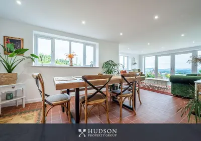 a dining room with a table and chairs and windows at Modern Snitton Cottage & Gardens in Ludlow
